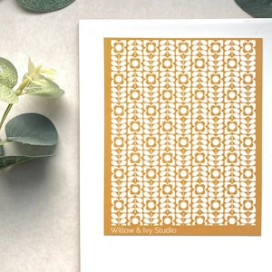 May include: A mustard yellow sheet of paper with a white repeating pattern of stylised flowers and leaves. The text "Willow & Ivy Studio" is printed at the bottom of the sheet.