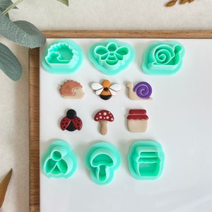 May include: A set of 10 green plastic cookie cutters featuring various nature-themed designs, including a bee, snail, mushroom, ladybug, and jar.