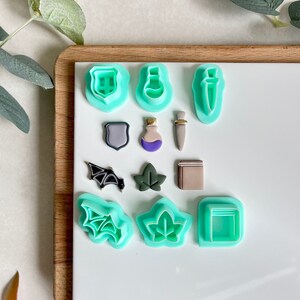May include: Set of 10 green plastic cookie cutters shaped like a shield, potion bottle, dagger, bat, leaf, book, and more.