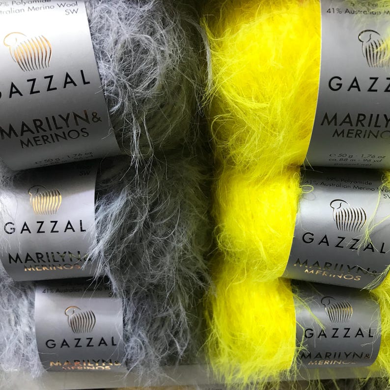 Puede incluir: Dos ovillos de hilo, uno gris y otro amarillo, con la etiqueta "GAZZAL MARILYN & MERINOS" en cada uno. El hilo es suave y esponjoso.