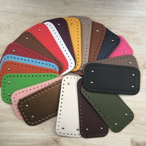 Peut inclure: Une collection de bases de sacs colorées, de forme rectangulaire et ovale, dans diverses nuances, notamment marron, rouge, vert et rose. Chaque base comporte des trous pré-percés et des rivets métalliques pour la fixation. Les bases sont disposées en éventail.