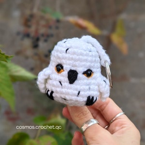 May include: White crocheted owl keyring with black eyes and a black beak. The owl is holding a silver key ring.
