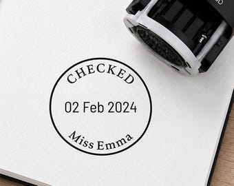 May include: A black and white self-inking rubber stamp with the model number RP-0030D. The stamp has created a circular black ink impression on white paper that reads CHECKED, 02 Feb 2024, and Miss Emma in a clear, professional serif font.