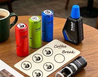 May include: Four cylindrical Trodat Printy self-inking stamps in red, lime green, blue, and black, alongside a black bottle of blue stamp ink. A rectangular card features the text Coffee Break and five circular icons of a steaming coffee cup.