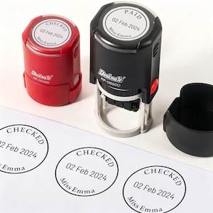 May include: A red self-inking stamp labeled CHECKED and a black self-inking stamp labeled PAID, both featuring the date 02 Feb 2024 and the name Miss Emma. The stamps are DeskMate RP-0030D models, shown with a black cap and three circular ink impressions.