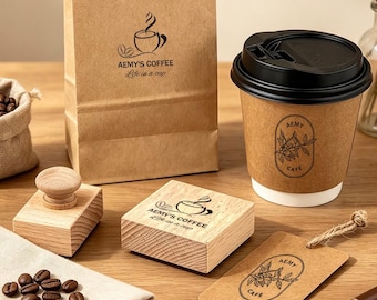 May include: A brown paper coffee bag with AEMY'S COFFEE Life in a cup text, a paper coffee cup with a black lid and AEMY CAFE label, two wooden stamps with coffee branding, a brown paper tag, a small burlap sack of coffee beans, and a pen.
