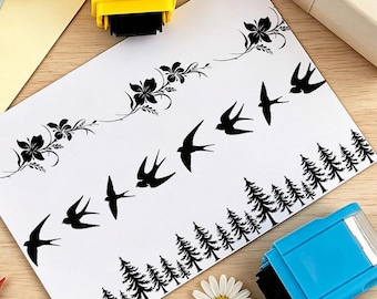 May include: A white rectangular sheet featuring black ink designs including floral vine borders, a flock of flying swallows, and a dense forest of pine trees. The sheet is positioned between a yellow stamp and a blue stamp with a white flower.