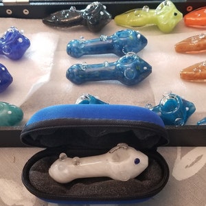May include: A collection of 11 colorful glass pipes in a black velvet-lined box. The pipes are all different colors and have a variety of designs. Some of the pipes have bubbles in them, while others have swirls. The pipes are all in a black velvet-lined box.