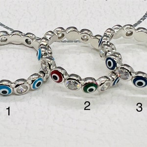 May include: Three silver rings with a circle of blue, white and black evil eye charms. The rings are numbered 1, 2 and 3.