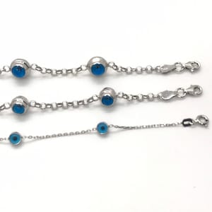 May include: Three silver chain bracelets with blue evil eye charms. The bracelets are different lengths.