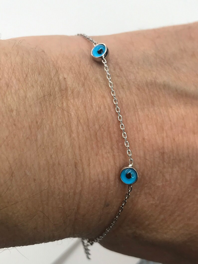 May include: A silver chain bracelet with three blue evil eye charms.