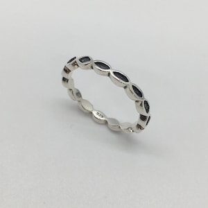 Peut inclure: Une bague en argent avec un motif répétitif de petites découpes ovales. La bague est marquée "925" à l'intérieur.