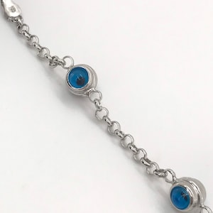 May include: A silver chain bracelet with three blue evil eye charms. The bracelet is made of a delicate chain and the charms are round with a blue glass center.