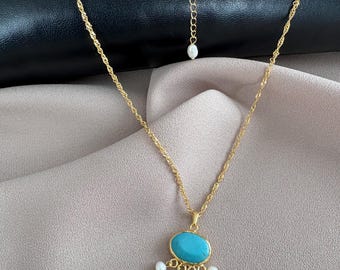 May include: A gold-toned twisted chain necklace featuring a central oval turquoise cabochon pendant. The pendant is accented with four small, dangling white freshwater pearls. An additional single pearl is attached to the adjustable chain extender.