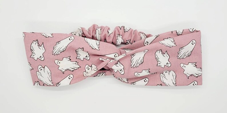 May include: A pink stretchy headband with a white ghost pattern.