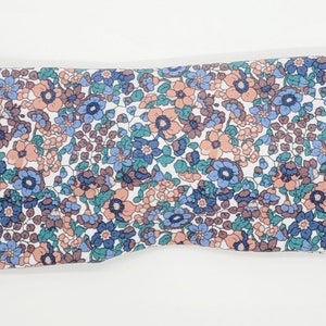May include: A white headband with a floral pattern in shades of blue, pink, and green.