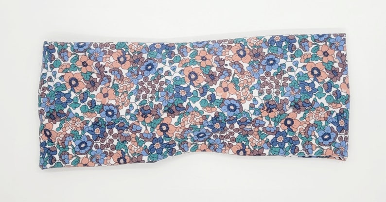 May include: A white headband with a floral pattern in shades of blue, pink, and green.