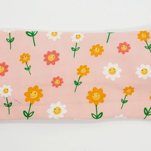 May include: A pink headband with a repeating pattern of yellow, orange, and white flowers with smiley faces.