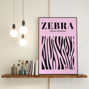 May include: A pink and black zebra print poster with the text "ZEBRA EQUUS QUAGGA" on a shelf with a wooden surface. There are three light bulbs hanging from the ceiling above the shelf.