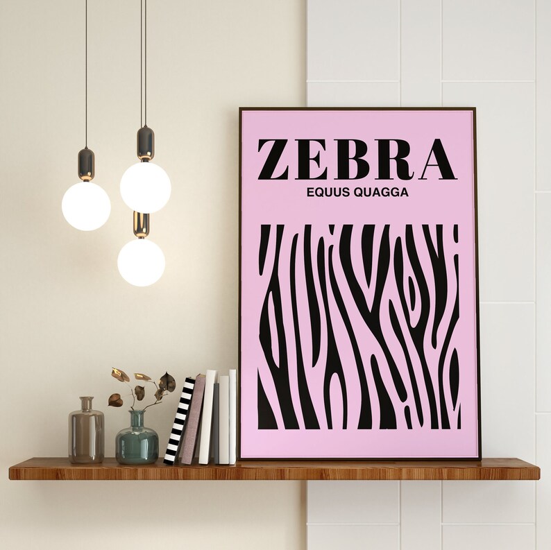 May include: A pink and black zebra print poster with the text "ZEBRA EQUUS QUAGGA" on a shelf with a wooden surface. There are three light bulbs hanging from the ceiling above the shelf.