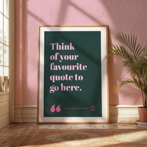May include: A rectangular wall art print in a gold frame featuring a dark green background with light pink text that reads: Think of your favourite quote to go here. Below the text are two pink quotation marks, a horizontal line, and the words NAME and ORIGIN.