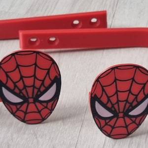 Könnte beinhalten: Zwei rote Plastik-Haarbandklammern mit einem Spiderman-Gesichtsdesign. Die Haarbandklammern sind rot und haben ein schwarzes Spinnennetzdesign.