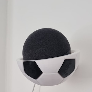 May include: A white football-shaped wall mount for a black smart speaker.