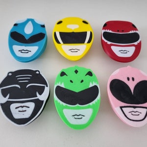 May include: Six colourful plastic figurines of the Power Rangers. Each figurine is a different colour and has a different ranger's helmet design. The rangers are: Blue, Yellow, Red, Black, Green, and Pink.