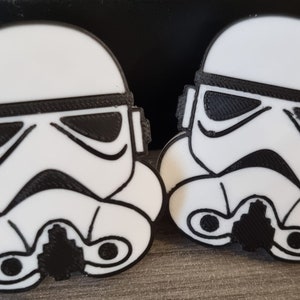 Op de afbeelding: Twee wit en zwart 3D-geprinte Star Wars Stormtrooper helm sleutelhangers.