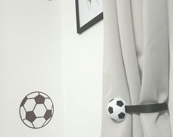 May include: A white wall with soccer ball decals and a framed print of a jersey with the name "HARRISON" and the number "8". A curtain is held back by a black strap with a soccer ball accent.