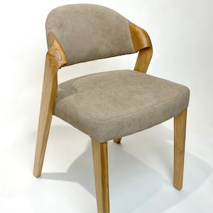 May include: A beige upholstered dining chair with a curved wooden back and four wooden legs.