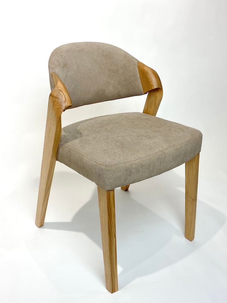 May include: A beige upholstered dining chair with a curved wooden back and four wooden legs.