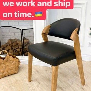 May include: A black leather chair with a curved back and wooden legs. The chair is sitting on a light wood floor. The text "No matter what, we work and ship on time." is displayed above the chair.