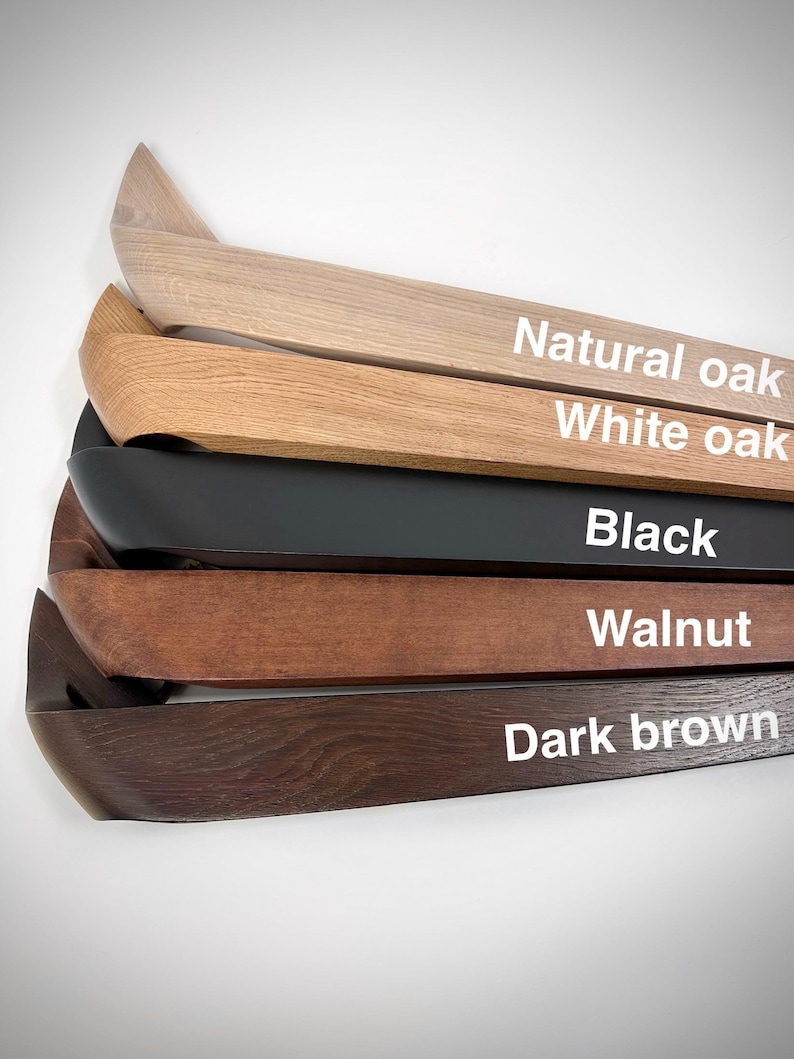 K&ouml;nnte beinhalten: Nahaufnahme von f&uuml;nf Holzregalen in verschiedenen Farben: Natureiche, Wei&szlig;eiche, Schwarz, Walnuss und Dunkelbraun. Jedes Regal hat ein gebogenes Design und der Farbname ist wei&szlig; aufgedruckt.