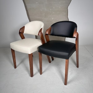 Peut inclure: Deux chaises avec des pieds en bois et des dossiers incurvés. Une chaise est blanche et l'autre est noire.