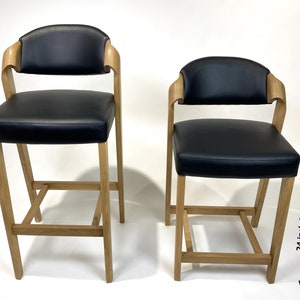 May include: Two black leather bar stools with wooden frames. The taller stool is 30 inches (76 cm) high and the shorter stool is 24 inches (61 cm) high.