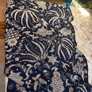 Peut inclure: Un tissu batik bleu et blanc avec un motif indonésien traditionnel. Le tissu présente un motif répétitif de fleurs et de feuilles stylisées.