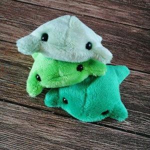 Pu&ograve; includere: Tre giocattoli di peluche a forma di razza. Il giocattolo in alto &egrave; verde chiaro, quello in mezzo &egrave; verde scuro e quello in basso &egrave; verde brillante.