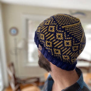 以下が含まれることがあります： 幾何学模様の青いニット帽。柔らかな糸でできており、快適なフィット感です。