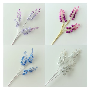 May include: Four sprigs of beaded floral stems, each with a different colour: purple, pink, blue, and silver.
