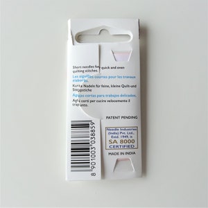 May include: A white cardboard package with a barcode and text in multiple languages. The text reads "Short needles for quick and even quilting stitches."  "Les aiguilles courtes pour les travaux elabores." "Kurze Nadeln fur feine, kleine Quilt-und Steppstiche" "Agujas cortas para trabajos delicados." "Aghi corti per cucire velocemente il trapunto."  "Patent Pending" "Needle Industries (India) Pvt. Ltd., Estd. 1949, is SA 8000 CERTIFIED MADE IN INDIA"
