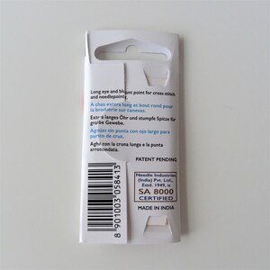 May include: White packaging with a barcode and text that reads "Long eye and blunt point for cross stitch and needlepoint."  "A chas extra long et bout rond pour la broderie sur canevas."  "Extra langes Ohr und stumpfe Spitze fur grobe Gewebe."  "Agujas sin punta con ojo largo para punto de cruz."  "Aghi con la cruna lunga e la punta arrotondata."  "Patent Pending"  "Needle Industries (India) Pvt. Ltd., Estd. 1949, is SA 8000 CERTIFIED"  "MADE IN INDIA"