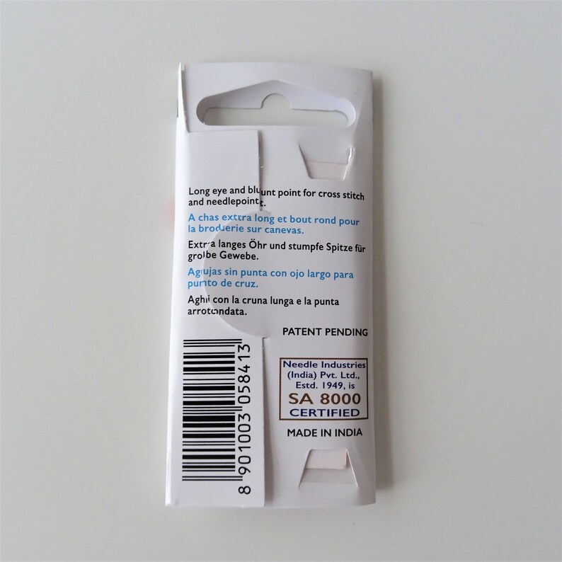 May include: White packaging with a barcode and text that reads "Long eye and blunt point for cross stitch and needlepoint."  "A chas extra long et bout rond pour la broderie sur canevas."  "Extra langes Ohr und stumpfe Spitze fur grobe Gewebe."  "Agujas sin punta con ojo largo para punto de cruz."  "Aghi con la cruna lunga e la punta arrotondata."  "Patent Pending"  "Needle Industries (India) Pvt. Ltd., Estd. 1949, is SA 8000 CERTIFIED"  "MADE IN INDIA"