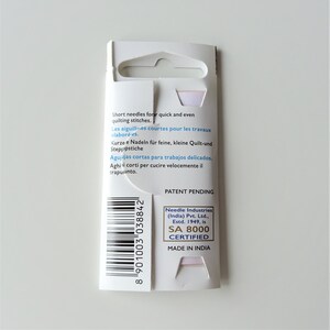 May include: A white cardboard package with a barcode and text that reads "Short needles for quick and even quilting stitches."  The package also includes the text "Patent Pending" and "Needle Industries (India) Pvt. Ltd., Estd. 1949, is SA 8000 CERTIFIED MADE IN INDIA".