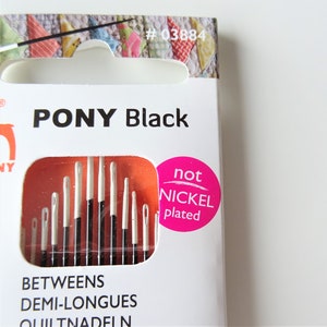 May include: A package of Pony Black quilting needles, labeled "Between Demi-Longues" and "Quiltnadeln". The package is white with a red and orange background and features a pink circle with the text "not nickel plated".