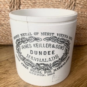 May include: White ceramic jar with a black and white label that reads "GRAND MEDAL OF MERIT VIENNA 1873 JAMES KEILLER & SON'S DUNDEE MARMALADE ONLY PRIZE MEDAL FOR MARMALADE LONDON. 1862"