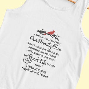 May include: White tank top with a black and red graphic design. The graphic features a cardinal bird on a branch with the text "A limb has fallen from our family tree that says grieve not for me remember the best times the laughter, the song the good life I lived when I was strong."