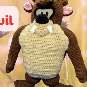 May include: A crocheted plush toy of Taz the Tasmanian Devil from the Looney Tunes cartoon. The toy is brown with a cream-colored chest and has pink ears and white fangs.