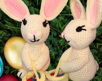 May include: Two crocheted Easter bunny toys with pink ears and baskets filled with colorful Easter eggs. The bunnies are sitting on a bed of green grass with painted Easter eggs scattered around them. The text "Easter Bunny PDF" is written in yellow letters on a white background.