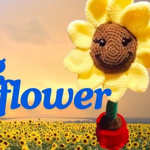 May include: A crocheted sunflower with a smiling face, yellow petals, and a green stem. The sunflower is standing in a red pot and is surrounded by a field of sunflowers.